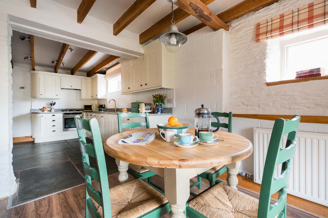 The dining table for four and open archway leading to cream kitchen in Quarry cottage at Flear Farm. 