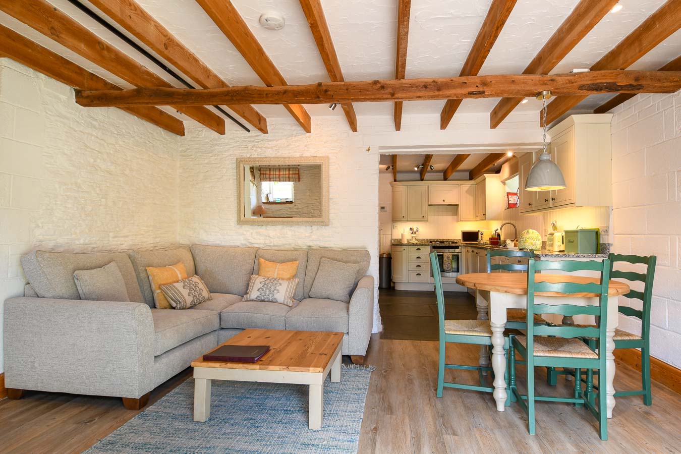 Quarry cottage's open plan living room with fresh colour scheme corner sofa and round table for four at Flear Farm holiday cottages.