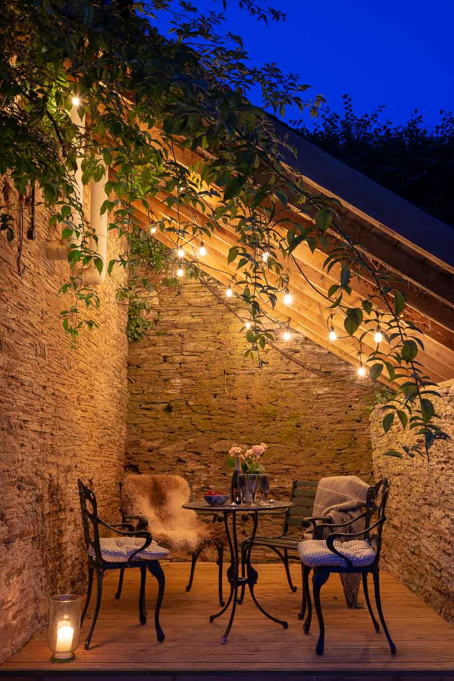 The lean too of the Linhay cottage at Flear Farm with iron furniture and festoon lights. 