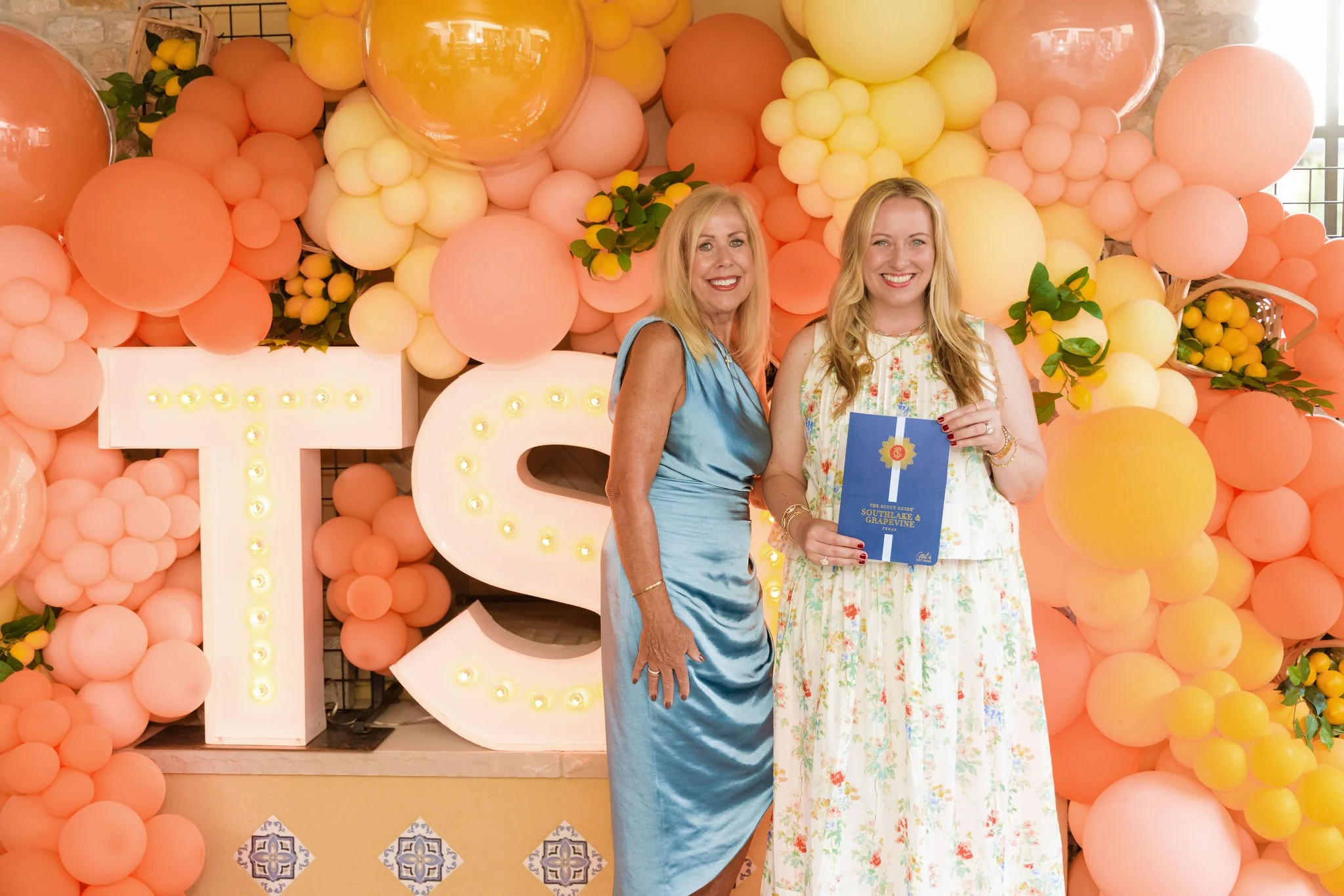 Guests celebrating The Scout Guide release beside TSG marquee letters and citrus-colored balloons.