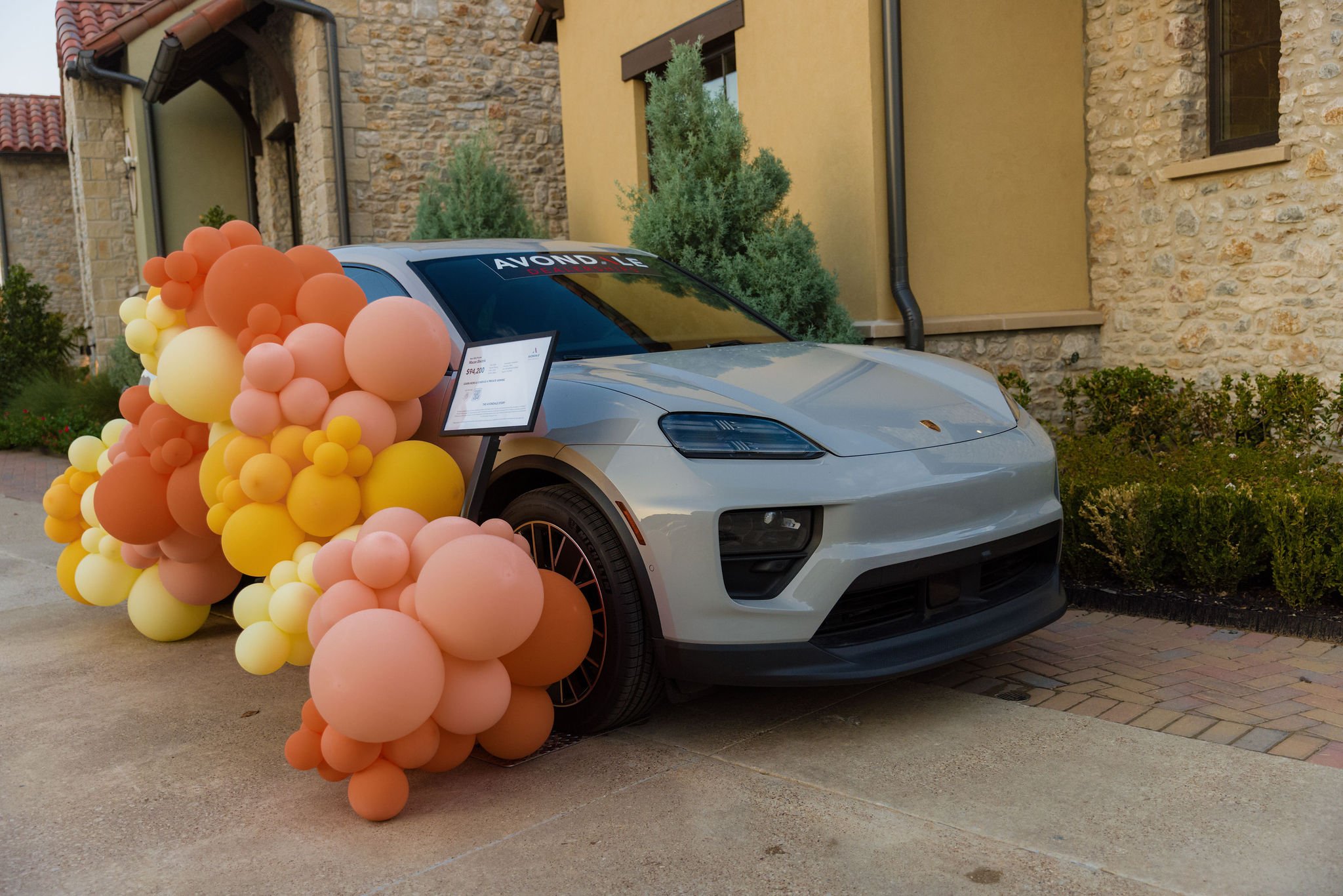 Peach, orange, and yellow balloon installation beside a Porsche at The Scout Guide release celebration.