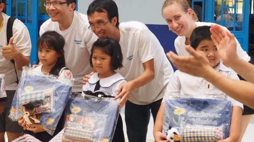 Quốc (center) poses with a local student after presenting her with her Sunflower Mission gift at the completion ceremony of the Tien Phuoc primary school.
