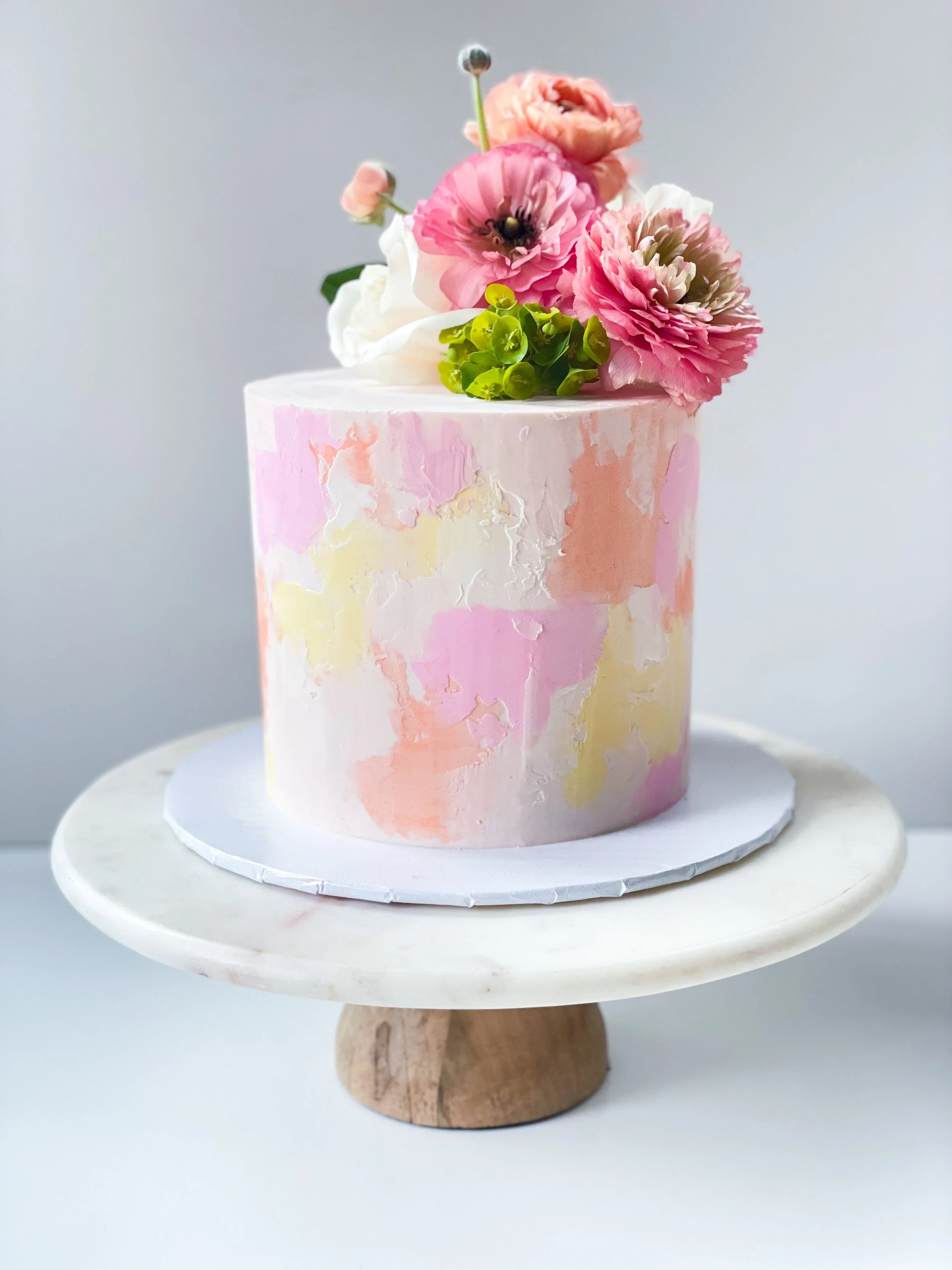pink and orange watercolor buttercream cake with fresh flowers