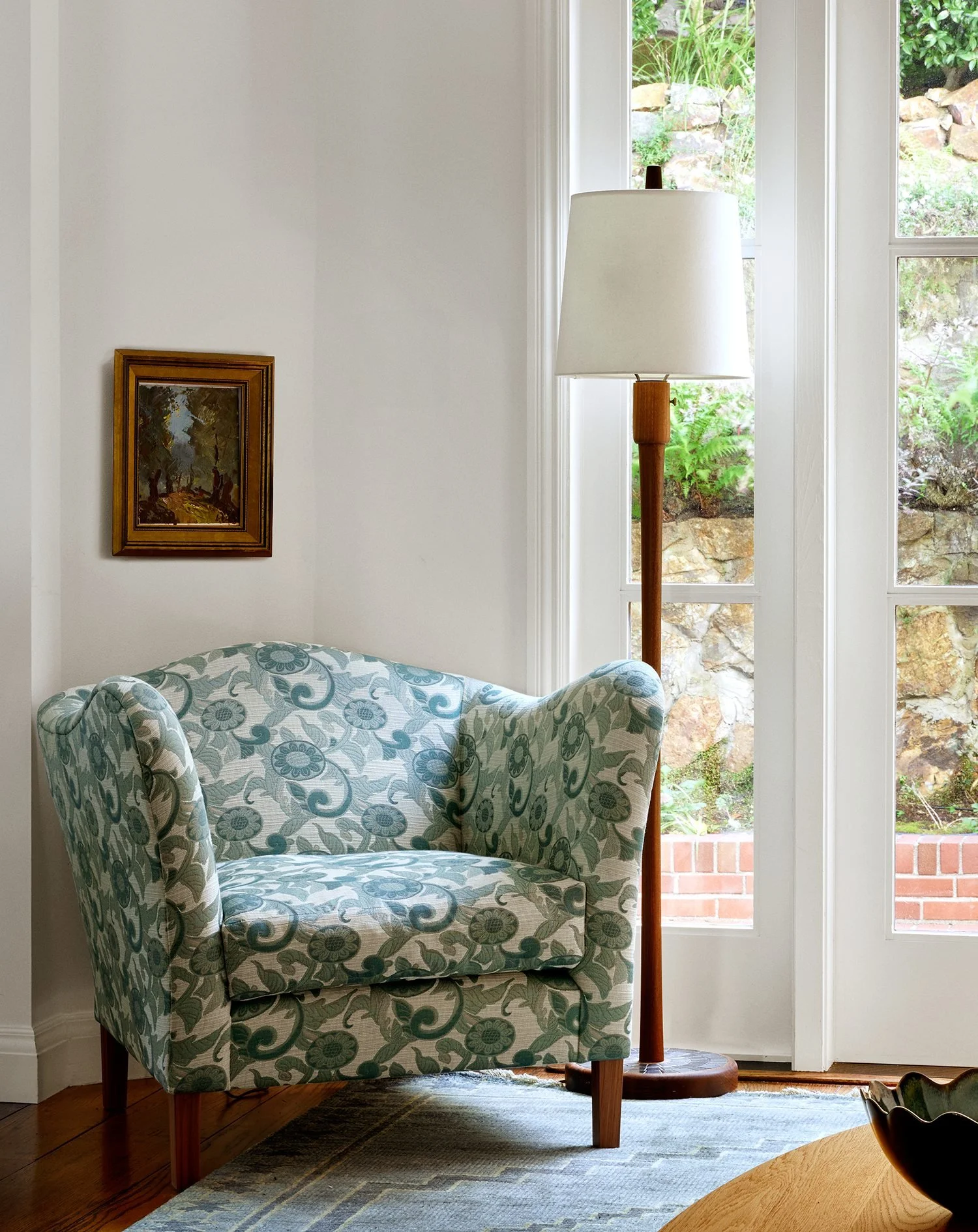 Floral upholstered armchair and wood floor lamp beside French doors to a terraced garden, San Francisco Spanish Revival