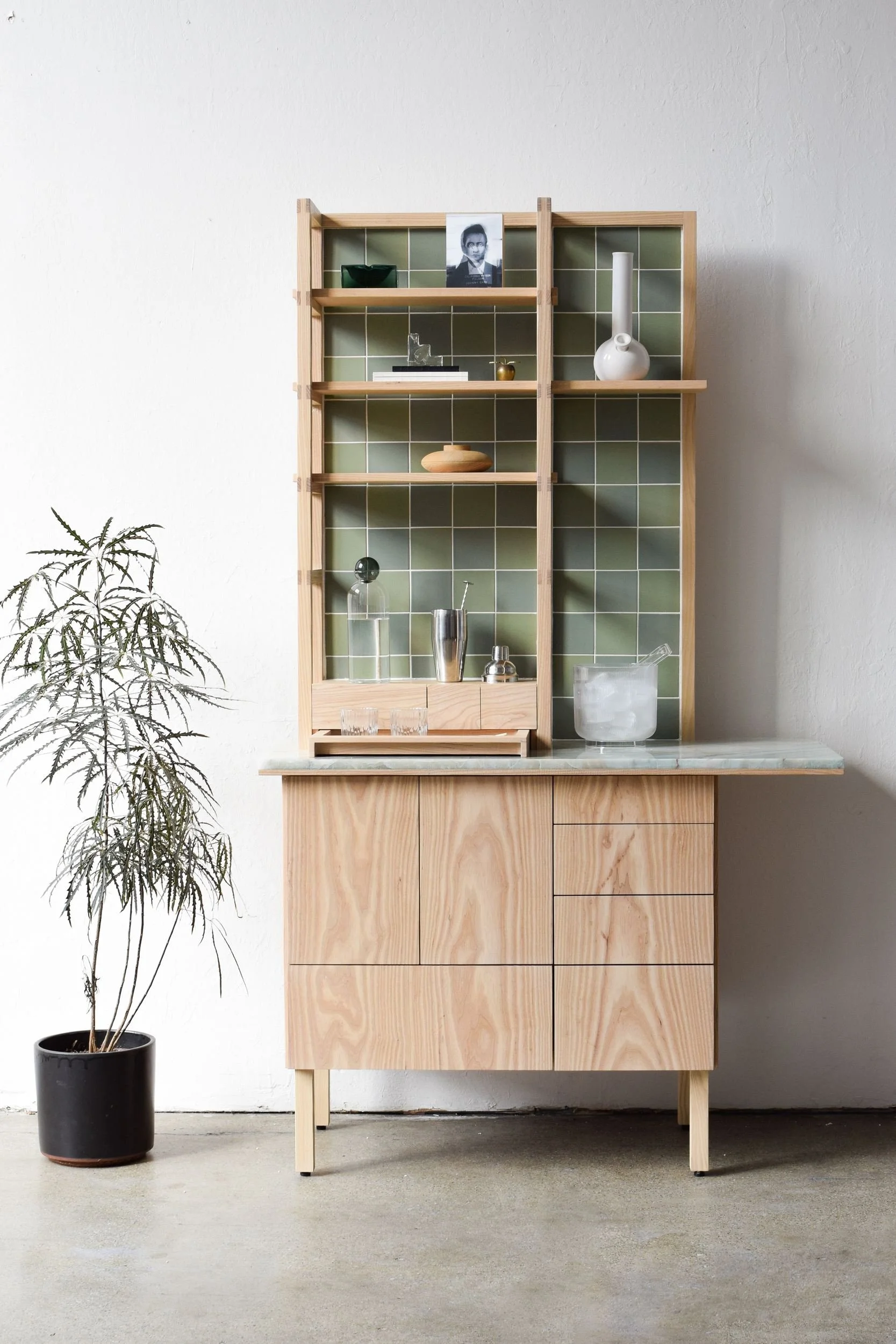 High Bar, a handbuilt cabinet for cannabis and spirits in pale wood with green tile shelving, by Alter Interiors