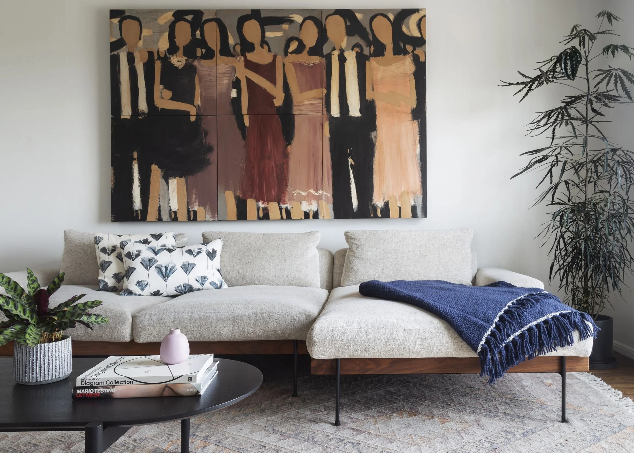 Living room with cream sofa beneath a large figurative painting, black coffee table and navy throw, Outer Sunset