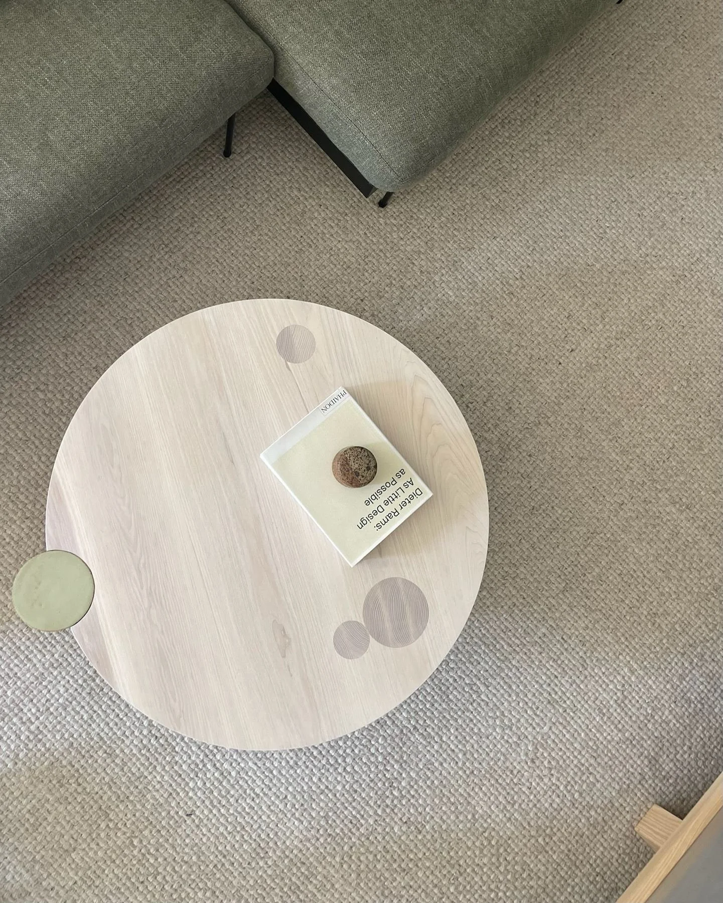 Overhead view of Hinterland's pale wood Ecliptic coffee table with circular inlays beside a green Croft House sofa