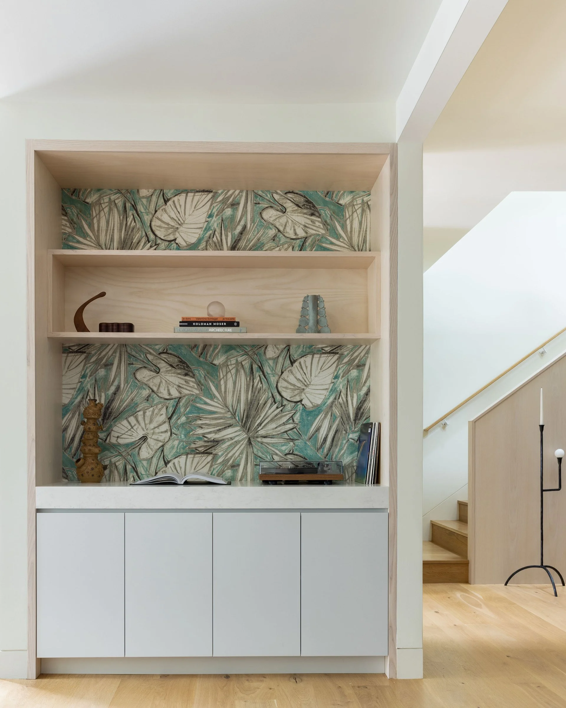 Built-in shelves lined with Pierre Frey Water Lily wallpaper beside the stair in a Cole Valley Edwardian