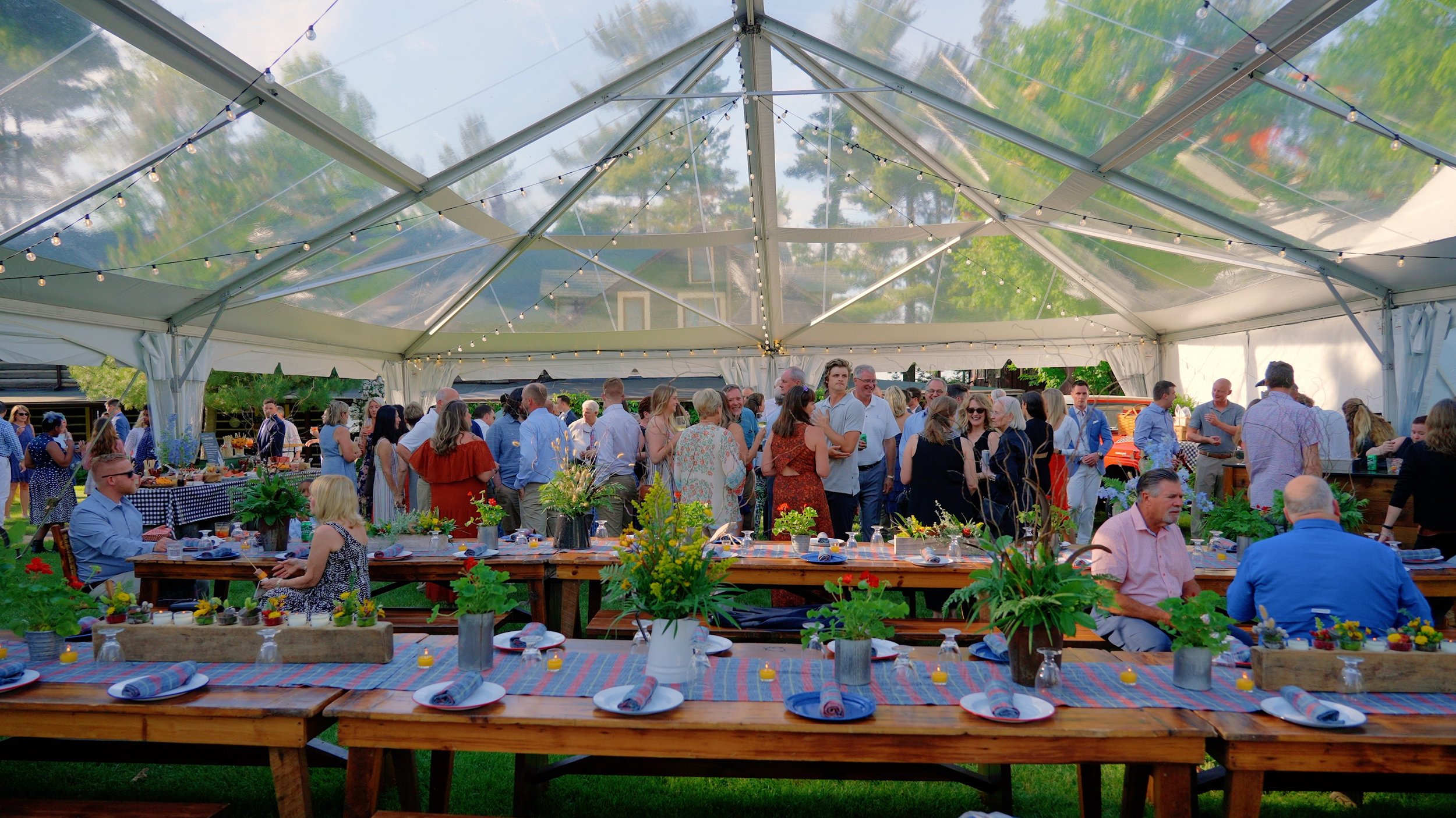 Guests at anOutdoor rehearsal dinner under a glass tent