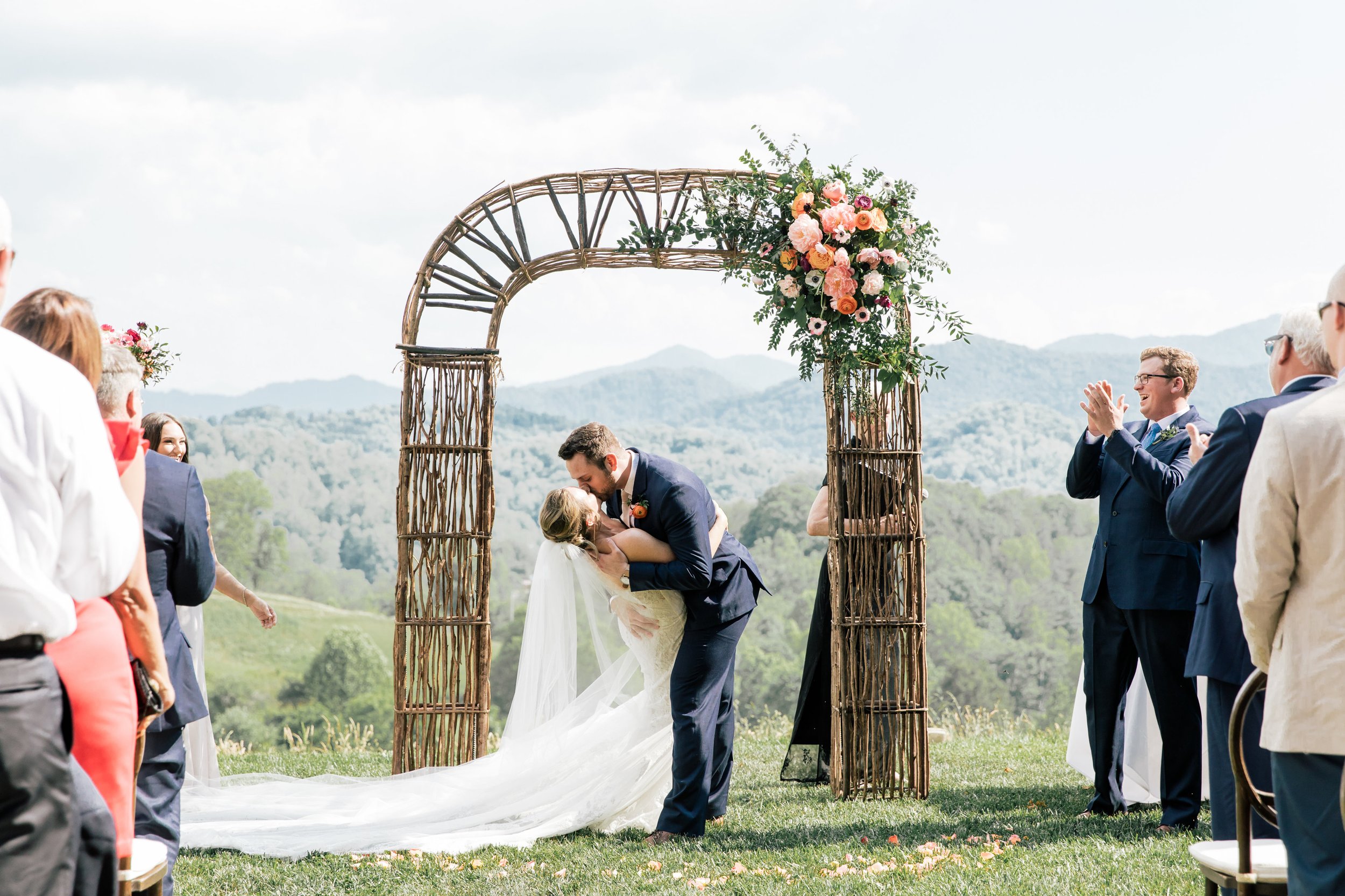 Bride and groom first kiss during their ceremony overlooking the mountains at The Ridge Wedding Venue