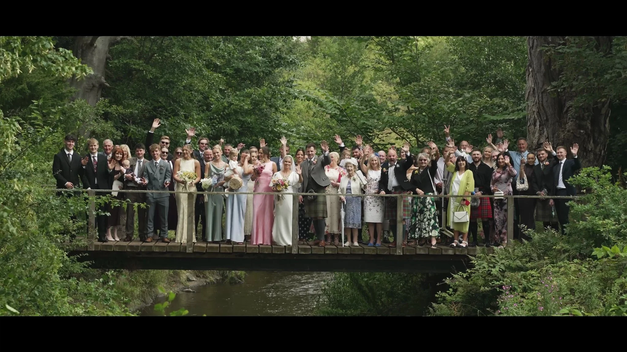 Wedding guests gathered on the wooden bridge at Colstoun House