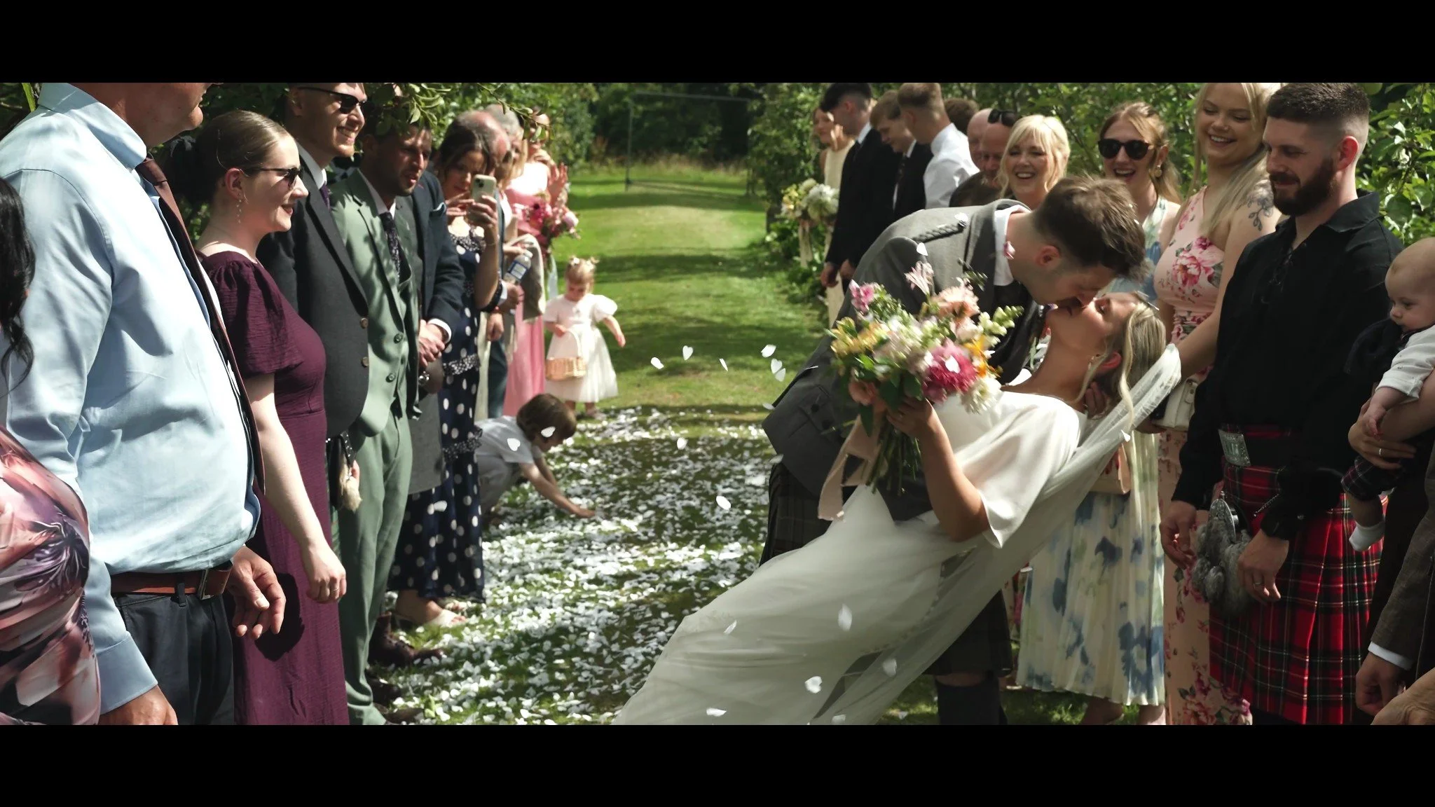 Rowan and Rhys walking between guests beneath a shower of confetti