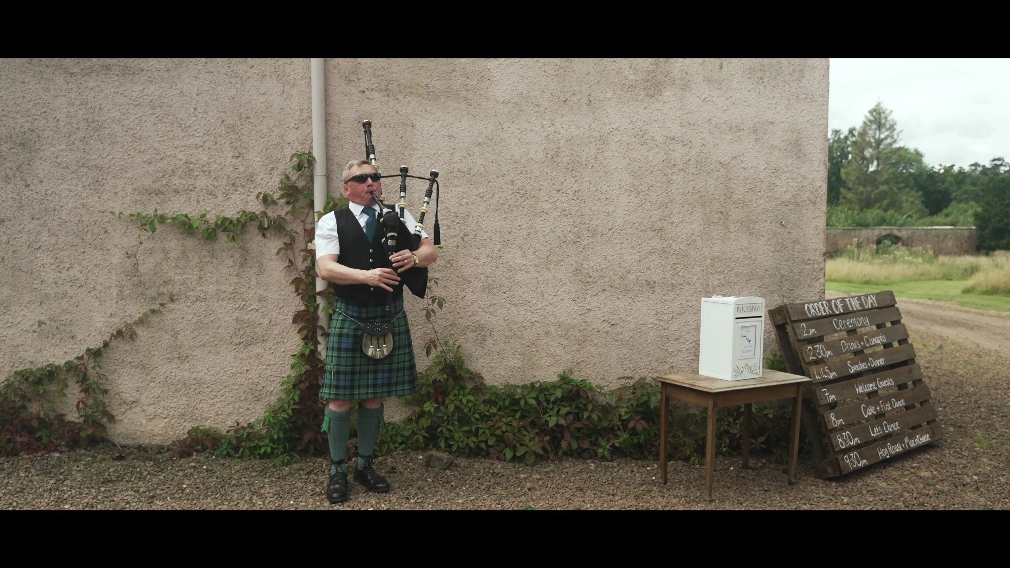 A piper playing beside a stone building at Colstoun House