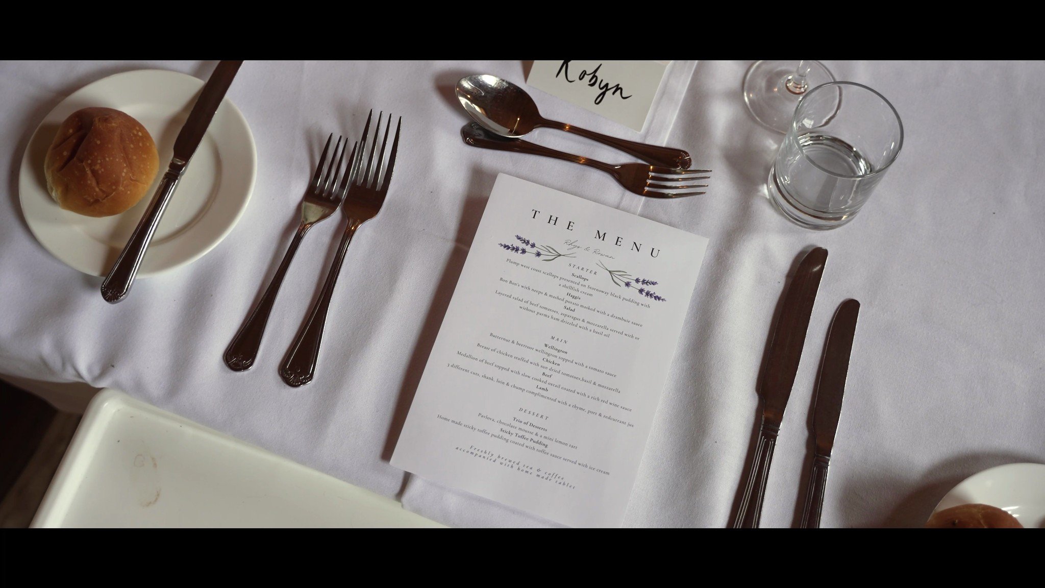 A wedding place setting with cutlery, glasses and a printed menu