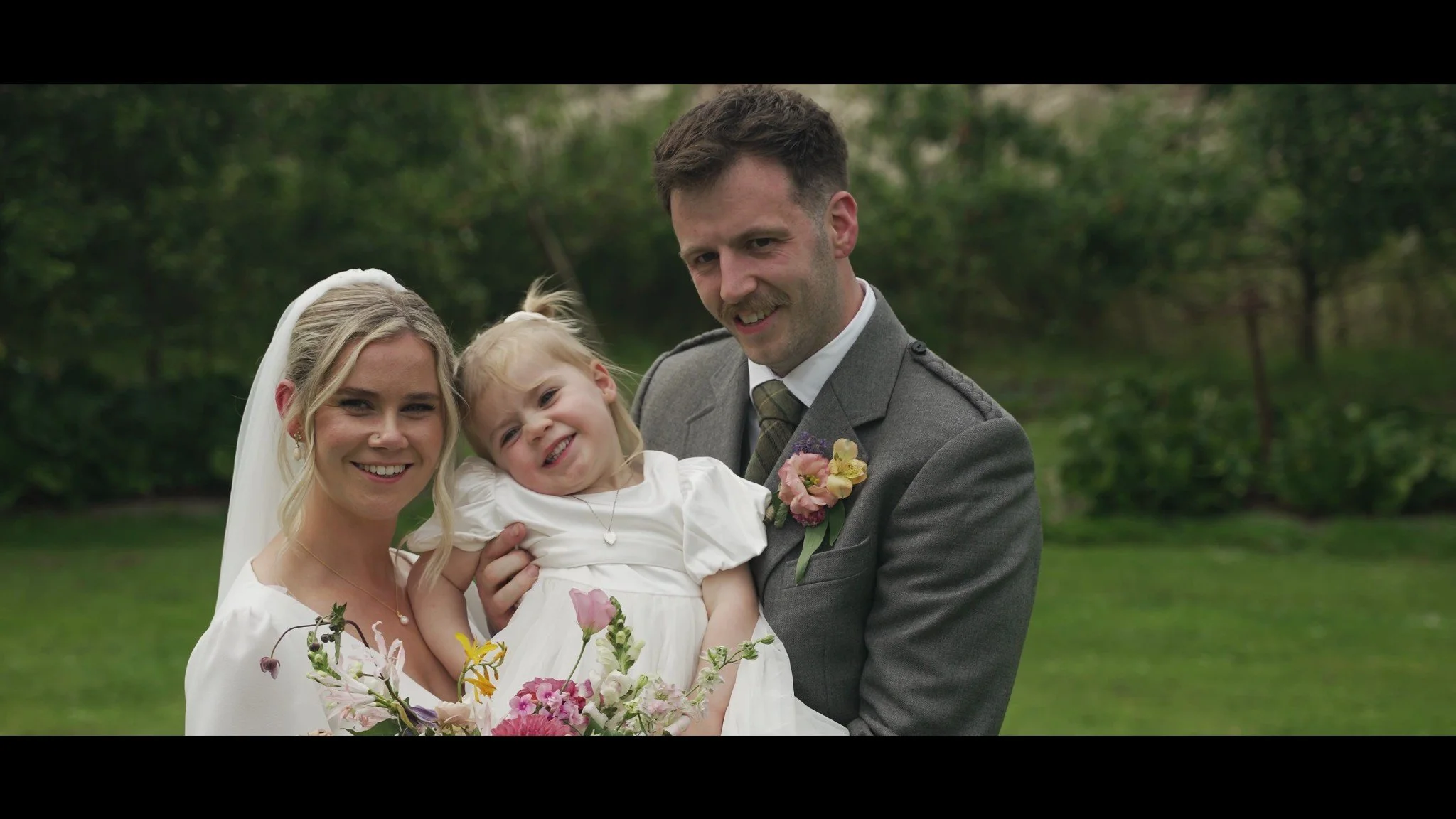 Rowan and Rhys smiling with their little girl at Colstoun House