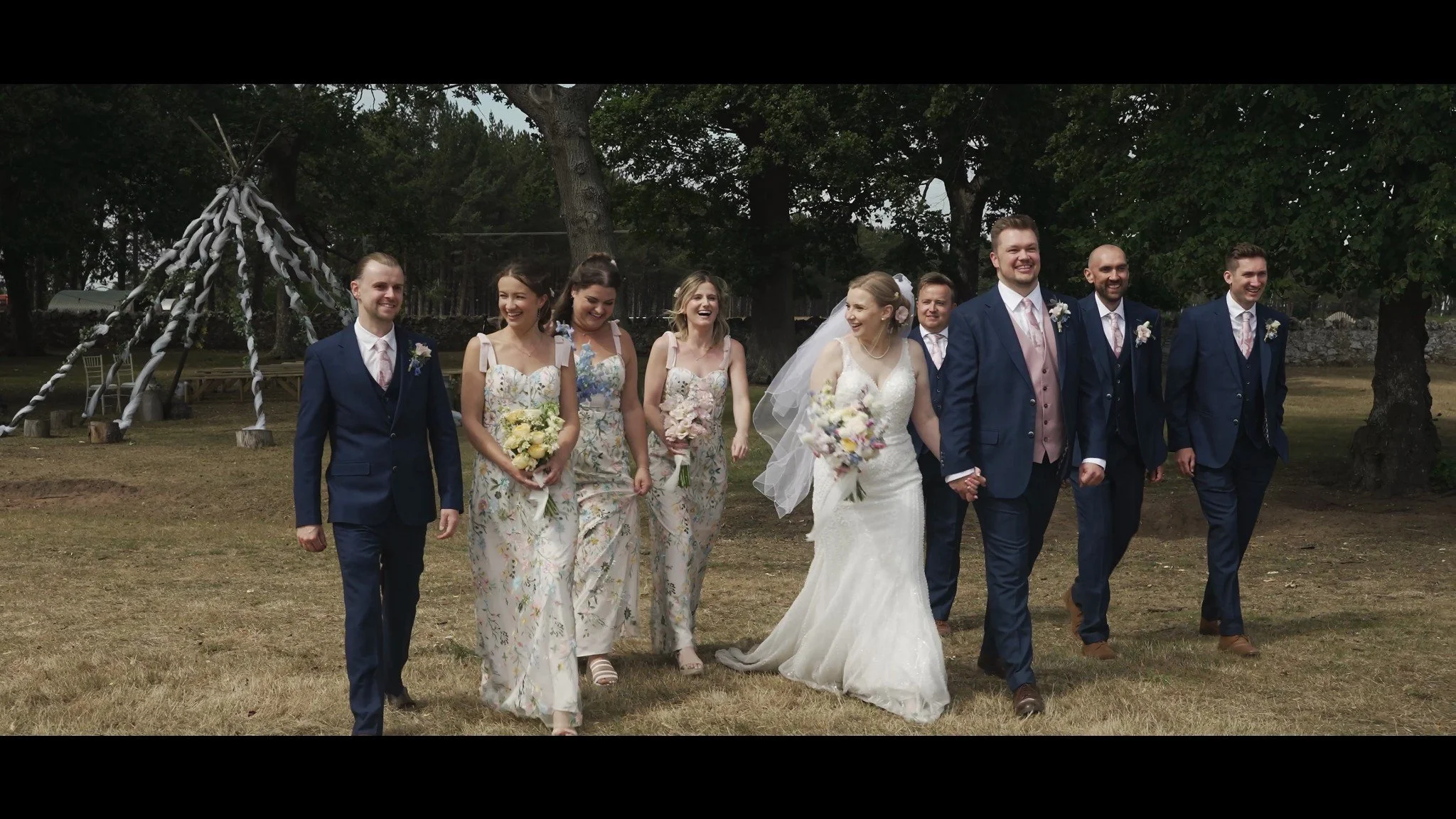 Hannah and David walking across the grounds with their wedding party