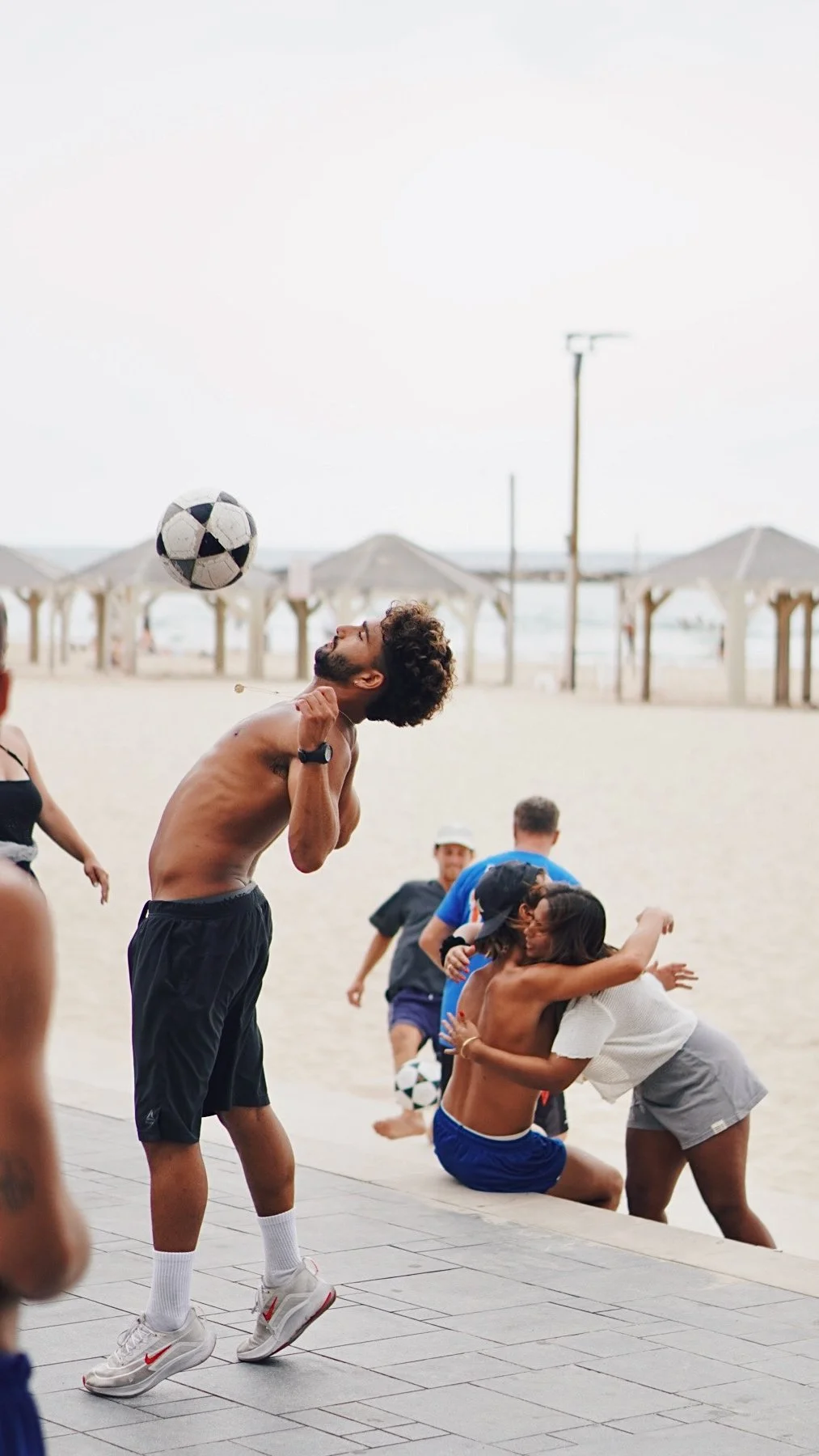 People playing soccer on a beach with umbrellas in the background
