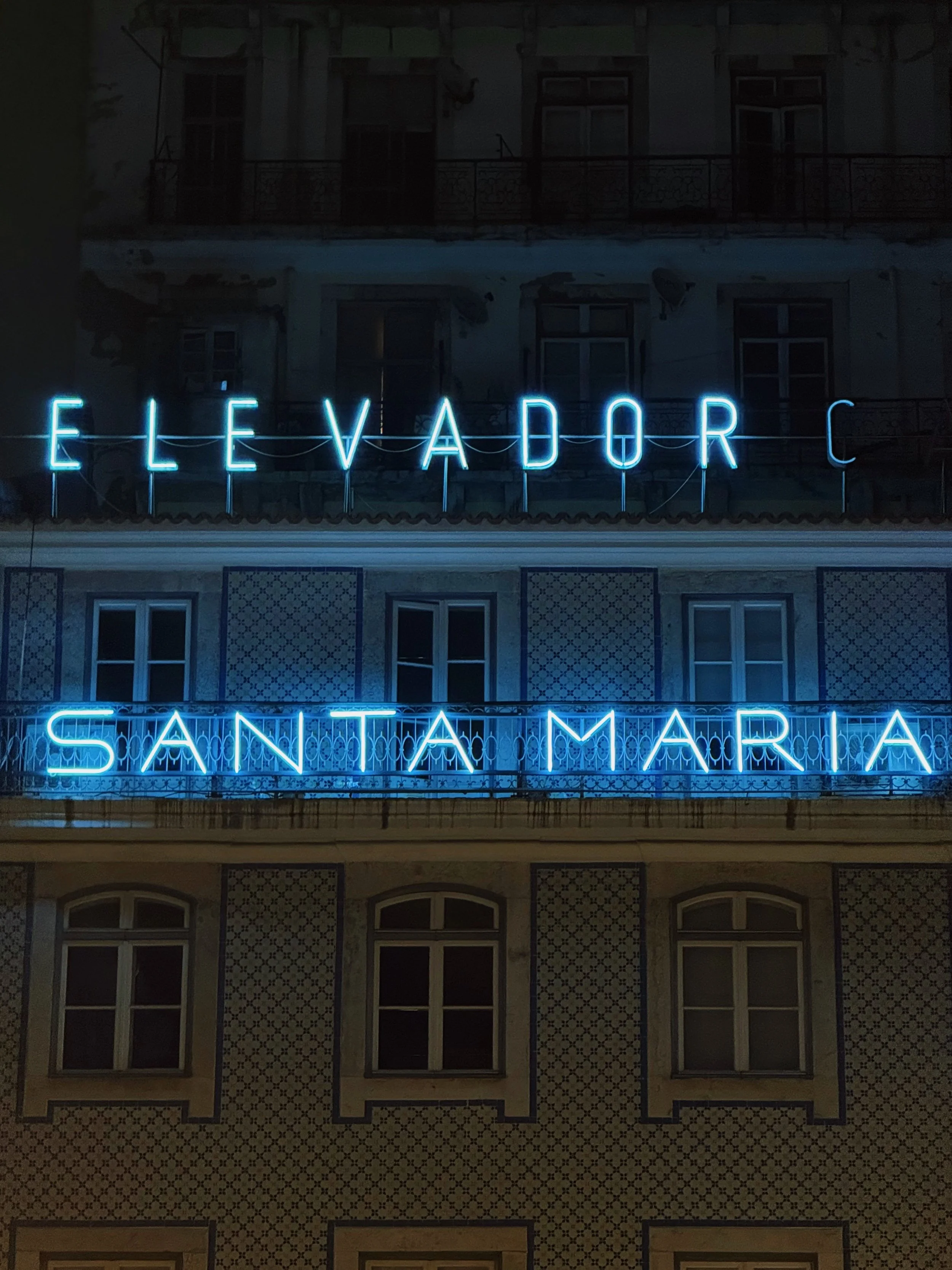 Neon sign on a building with the words 'Elevador Santa Maria' in blue lights, at night.