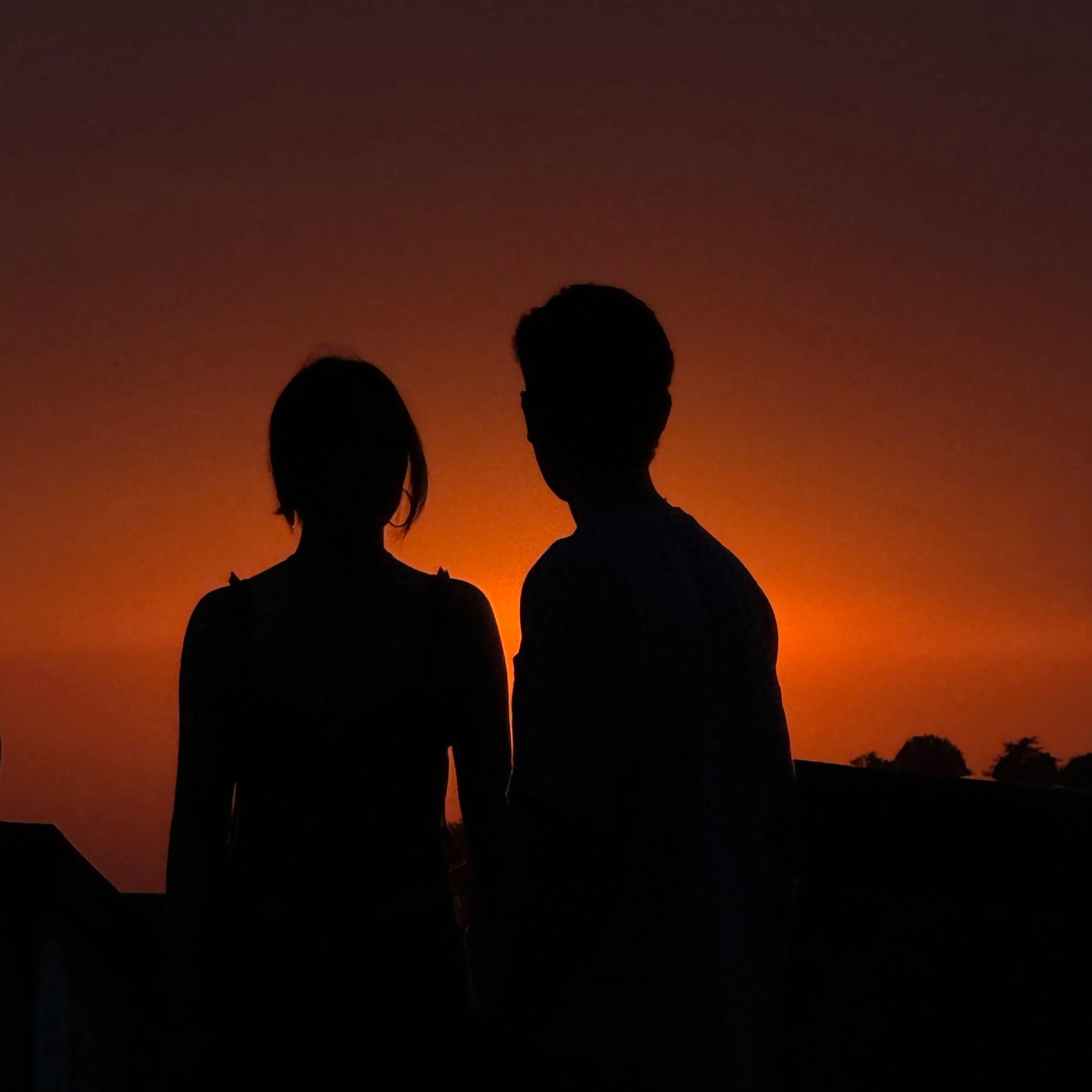 Silhouetted couple at sunset, photographed in a documentary style.