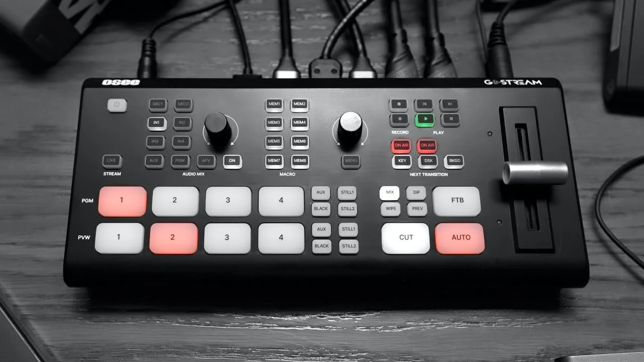 Audio control device with various buttons, knobs, and a slot, connected to multiple cables on a wooden surface.