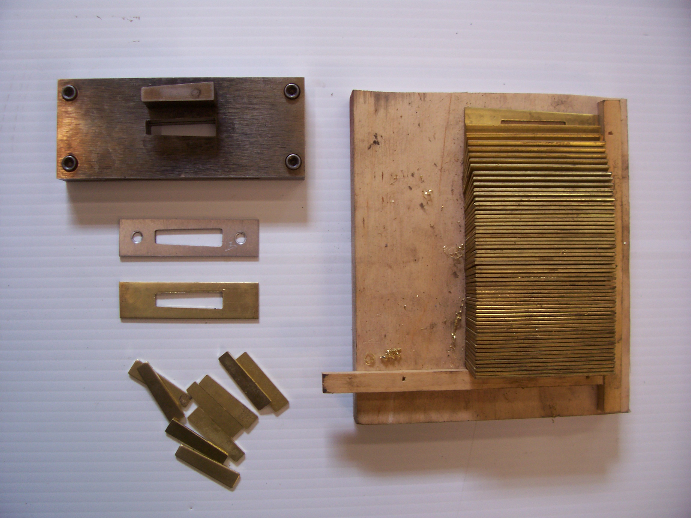 This image and the next five are an expression of what we will do to broaden our skills base at a bit of financial loss. These escutcheons could have been bought with the latches, but at the job we only need these. We fabricated a punch die from hardened steel to create the tapered relief in the plate. Using a simple hydraulic press we could do 50 in an hour — pretty fun and knowledge gained.