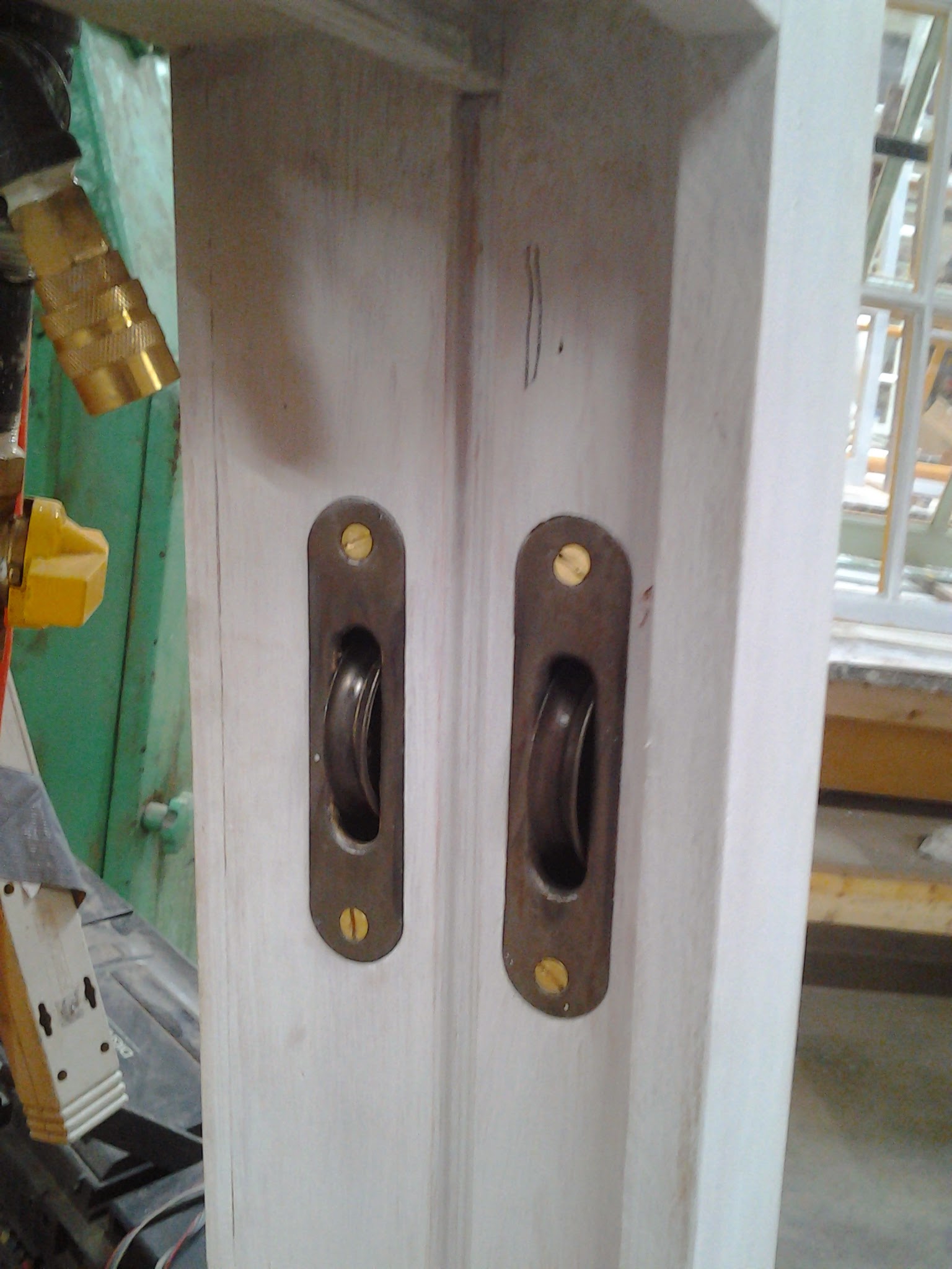 This is a nice look, though not historic. The cast iron pulleys are tumbled, cleaned, and lacquered. Solid brass and slotted screw finishes it off — works even better in a stained jamb.
