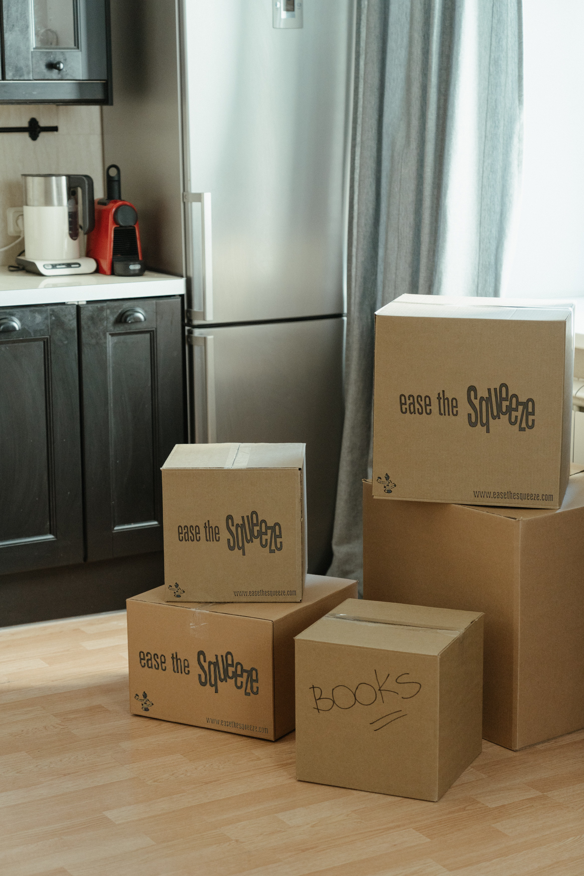 Neatly labelled Ease the Squeeze storage boxes stacked in a kitchen ready for collection