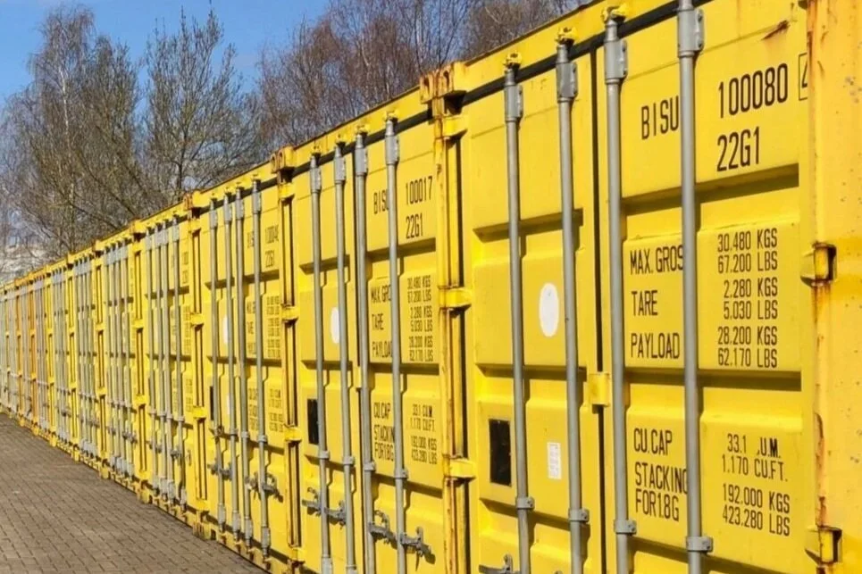 Row of secure yellow shipping containers at Ease the Squeeze Ely, offering easy drive-up access for business stock and equipment.