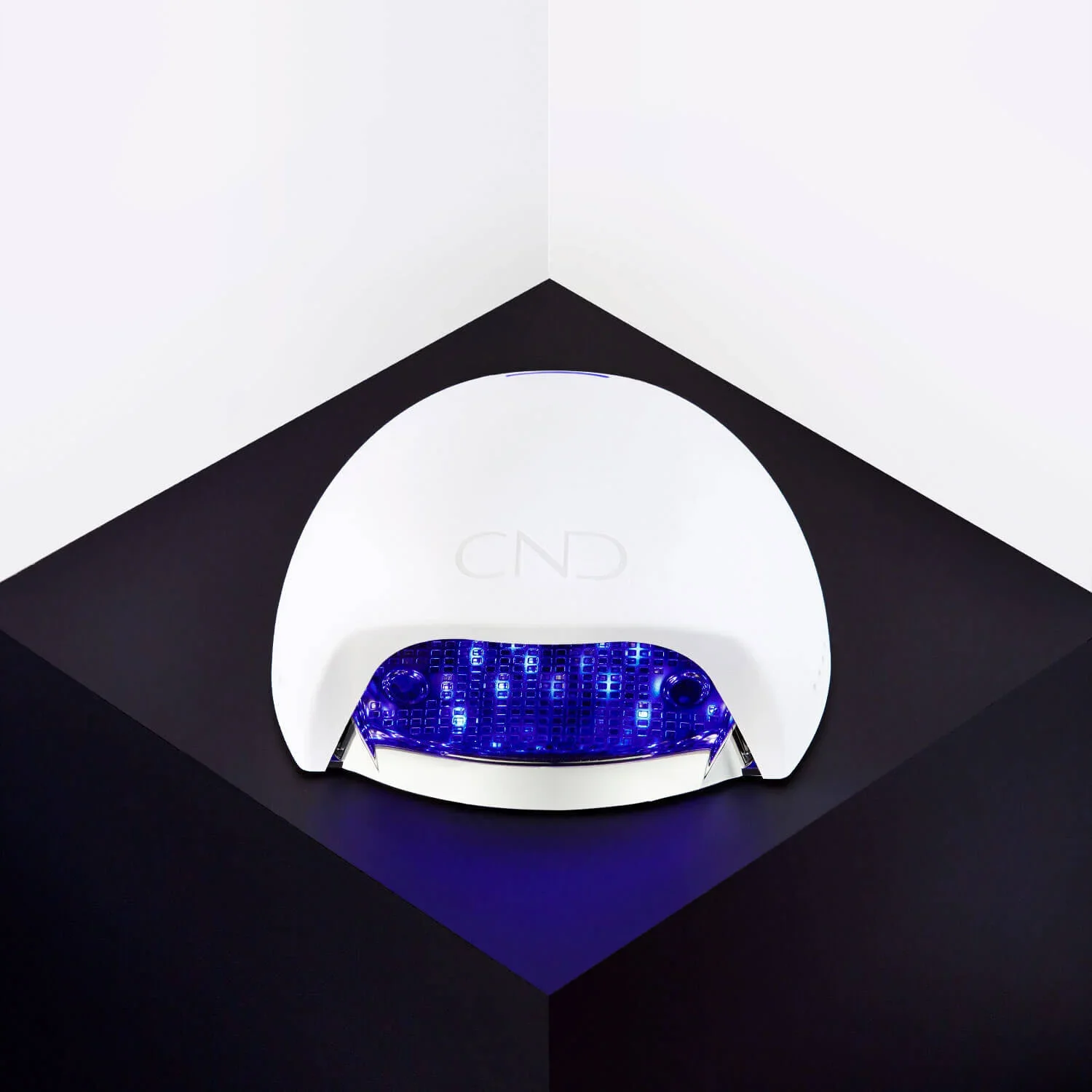 A modern, white, computer or electronic device with blue LED lighting, placed on a black surface with a dark background.