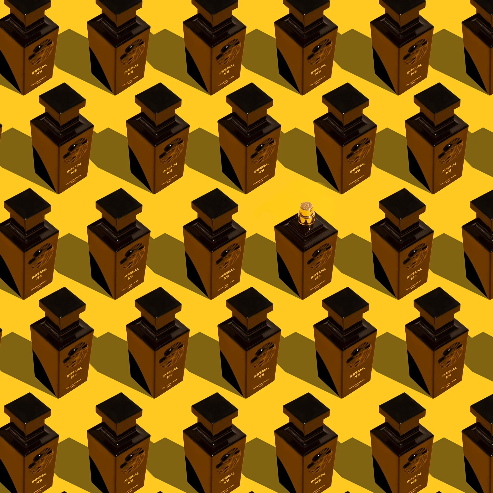 Multiple black and gold perfume bottles arranged in a grid pattern on a yellow background, with a single small round object at the bottom center.