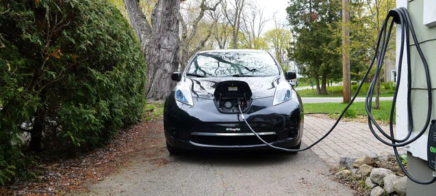 Electric vehicle plugged into a Level 2 home charger in a residential driveway