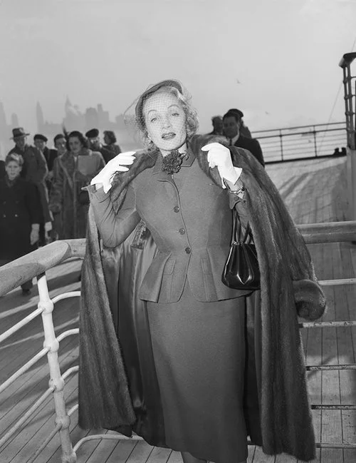 Marlene Dietrich wearing a day suit by Christian Dior onboard the Queen Elizabeth arriving in New York 21 December 1950, Getty Images