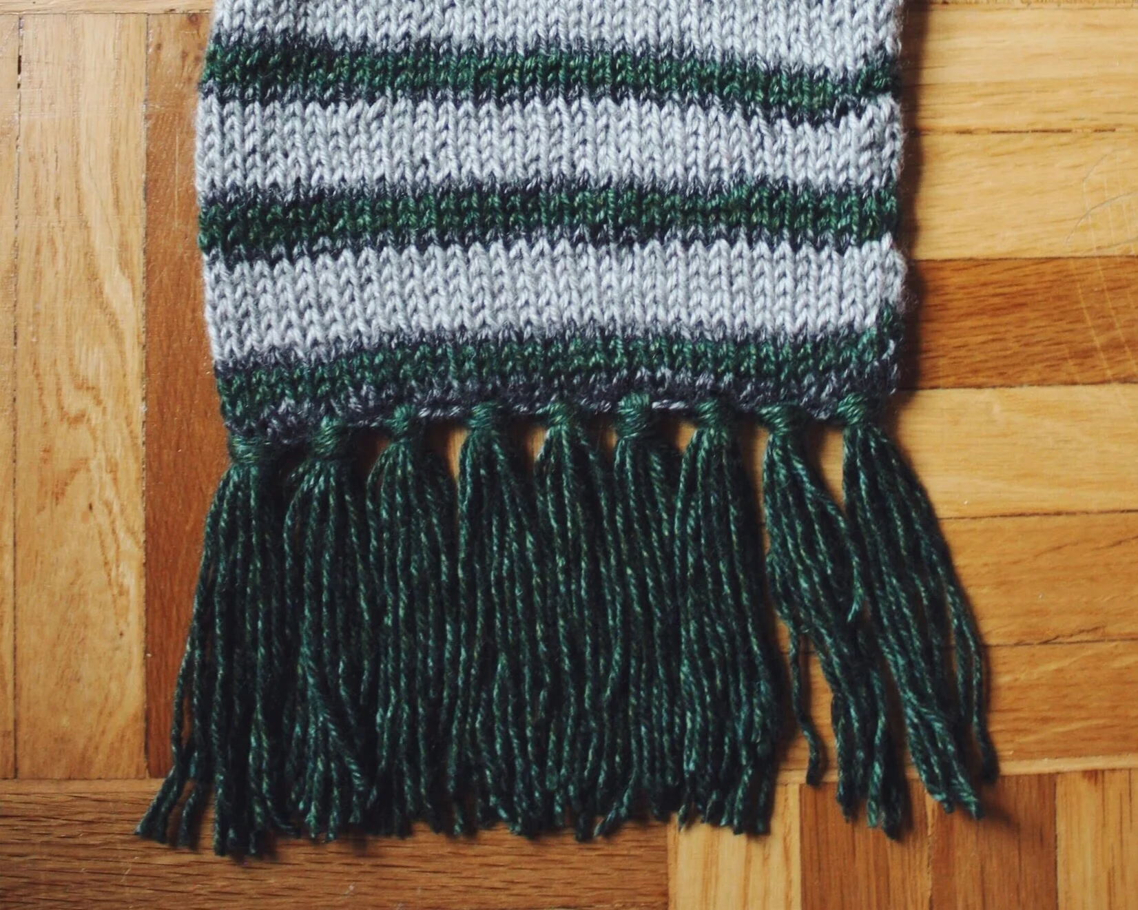 Why buy a Hogwarts scarf when you can make your own? Pictured is a finished Slytherin “Cursed Scarf.” Pattern here for free on emmmysue.com