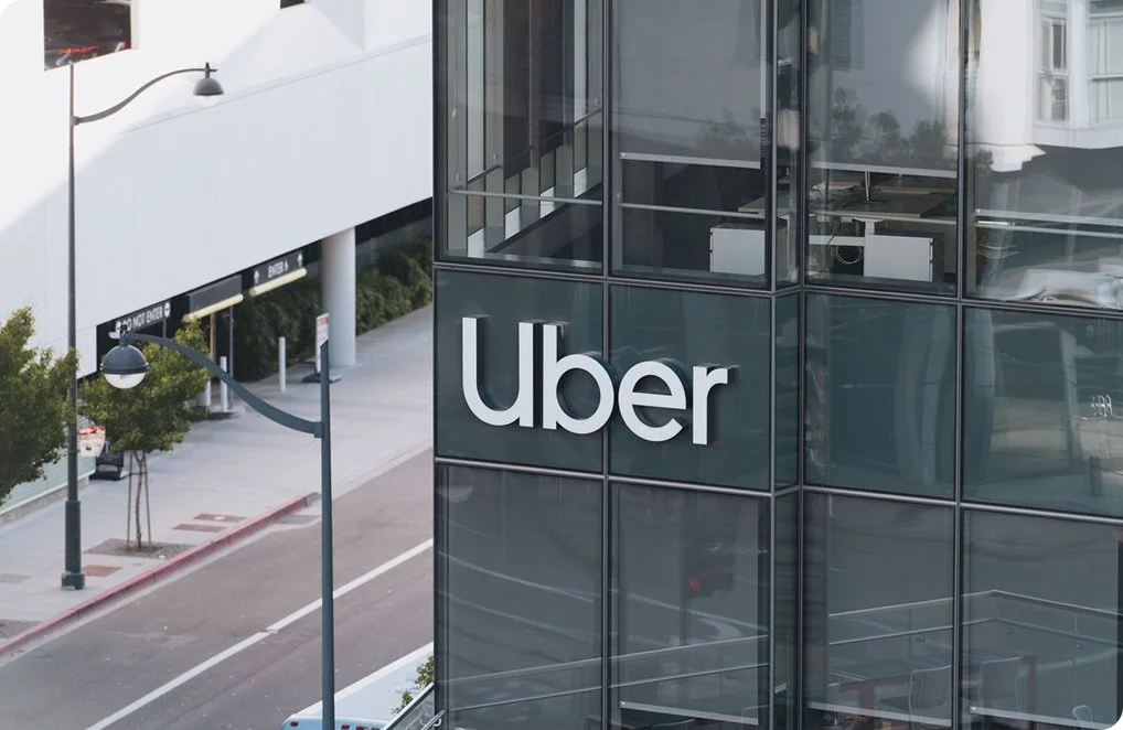 Uber headquarters building with logo on glass facade in an urban setting.