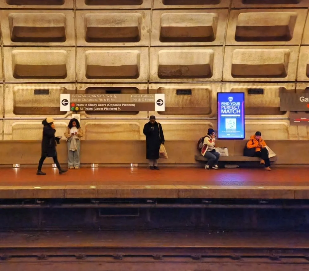 Commuters standing on a WMATA subway platform, engaged in conversation while waiting for their train to arrive.