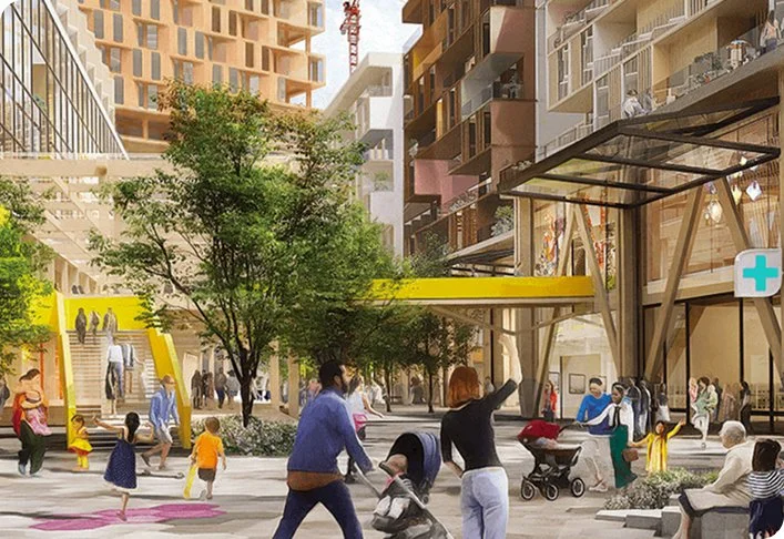 Urban plaza with people walking, trees, modern buildings, families with strollers, and a pedestrian bridge.
