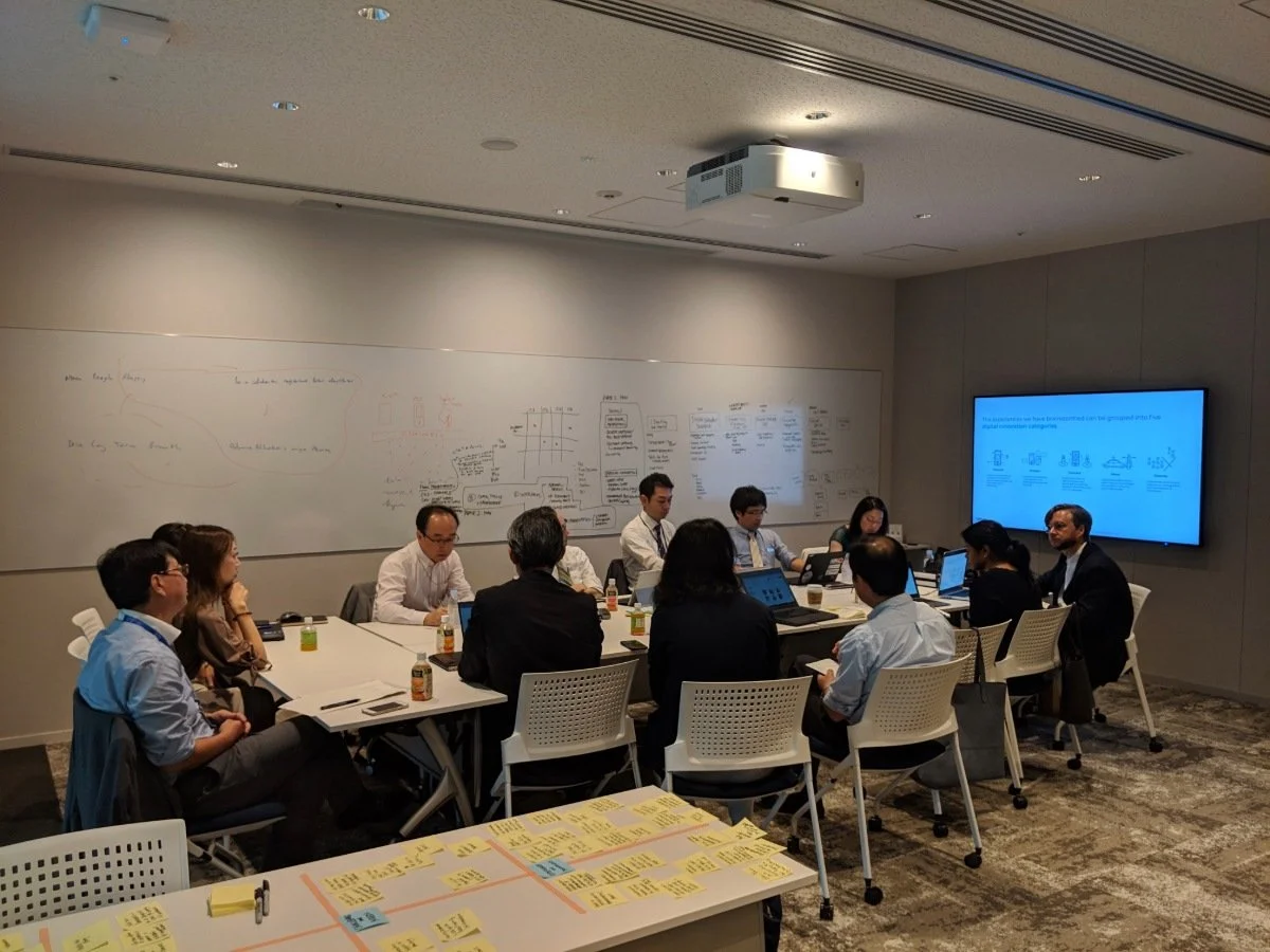 UrbanSense team gathers at a table with laptops, immersed in work within the urban environment of Nihonbashi, Tokyo.