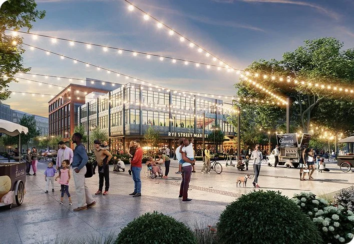 Outdoor plaza with people enjoying an evening at the Rye Street Market, featuring string lights, food stalls, trees, and a modern brick building in the background.