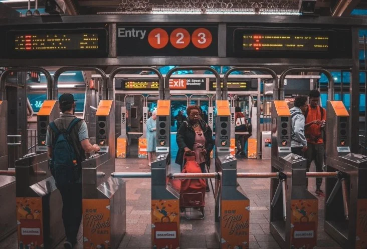 Passengers entering through subway turnstiles at a station with signage for lines 1, 2, and 3.
