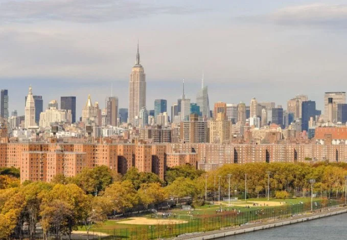 A view of the New York City skyline from the water, showcasing iconic buildings against a clear sky.