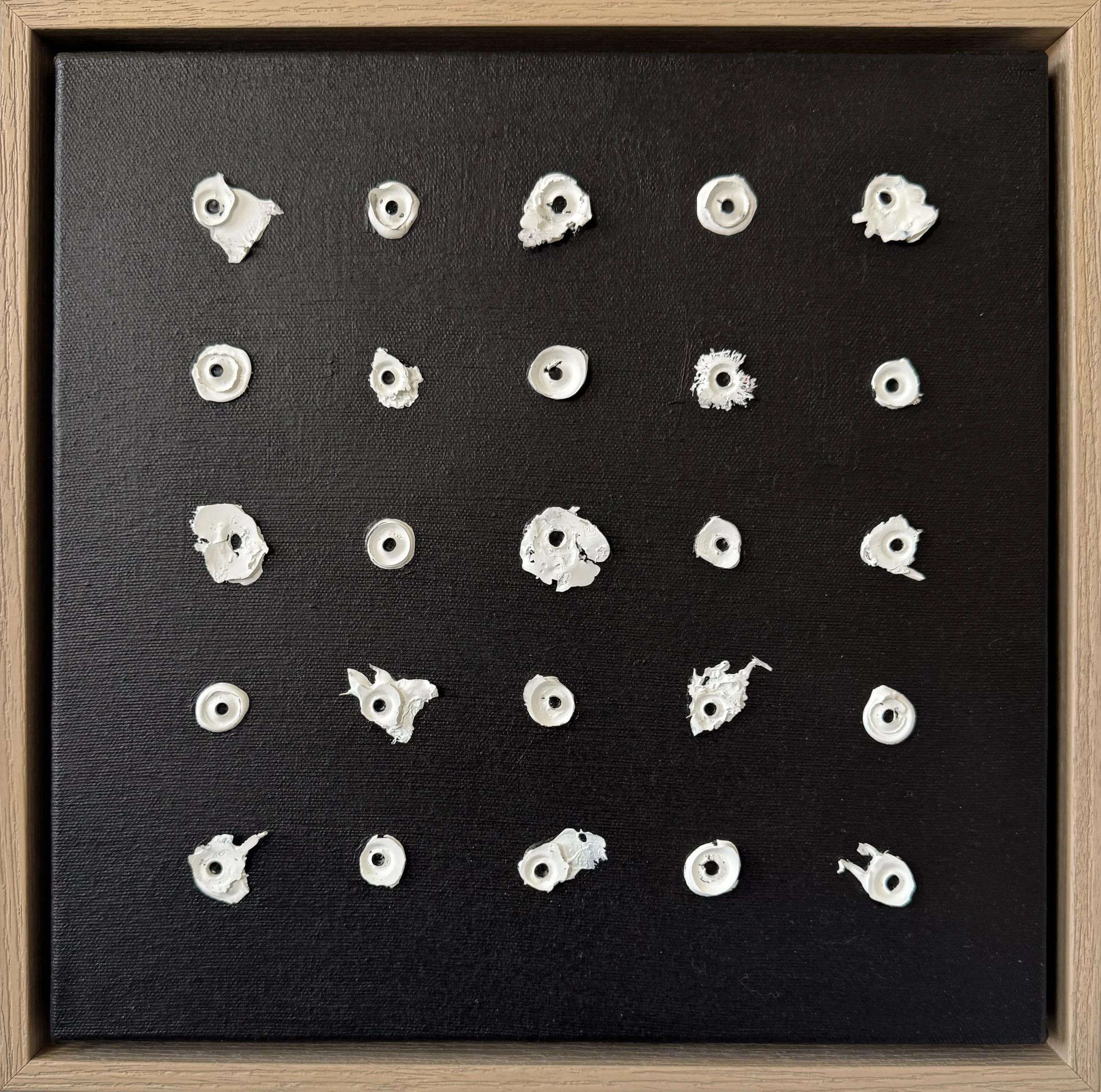 Square original painting on canvas displaying five rows and five columns of white organic circles of dried acrylic paint on a black background, mounted on a canvas within a light wood frame.