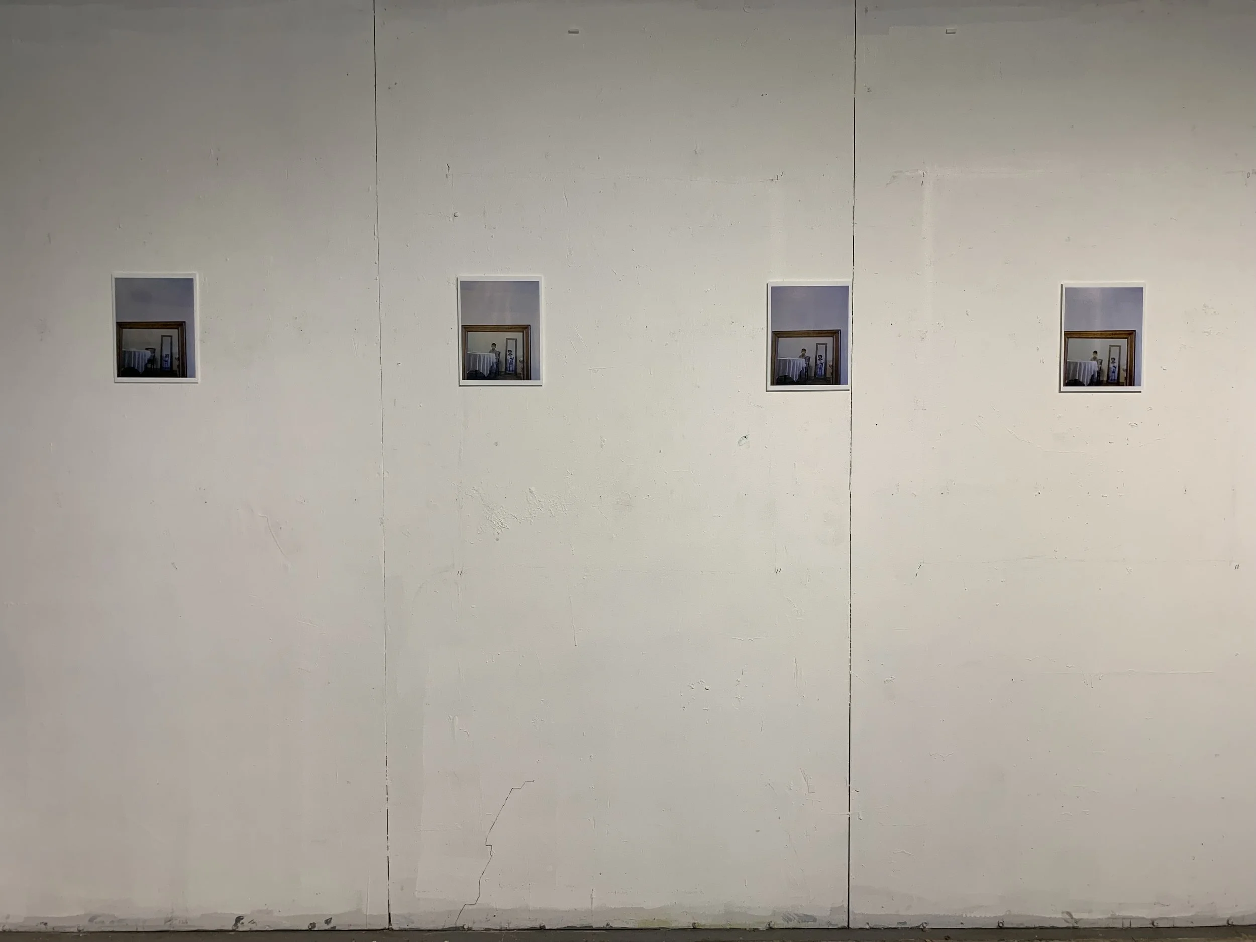 Four small framed pictures arranged in a row on a plain white wall.