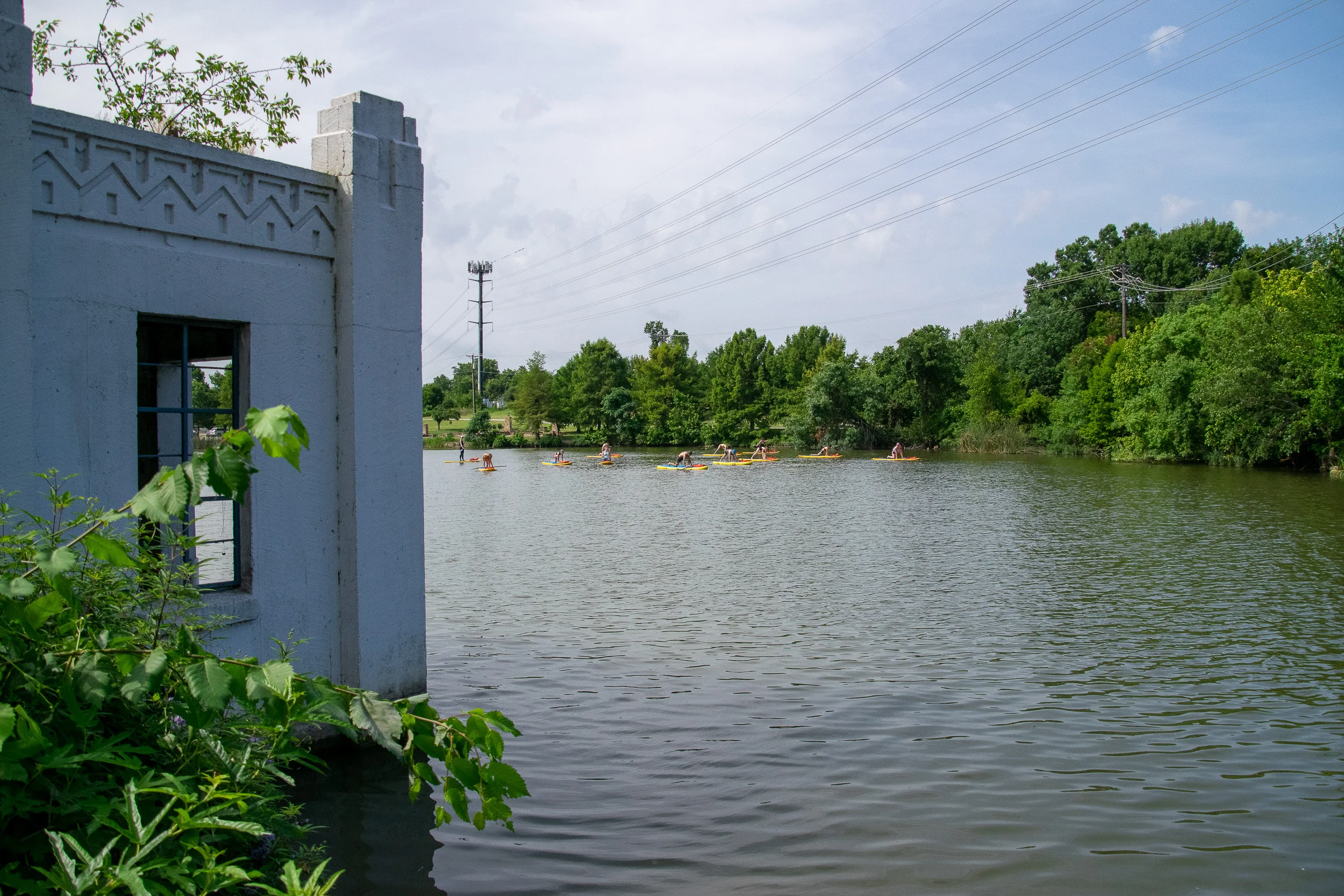 White Rock Lake boathouse with yogis practicing on paddle boards in the background.