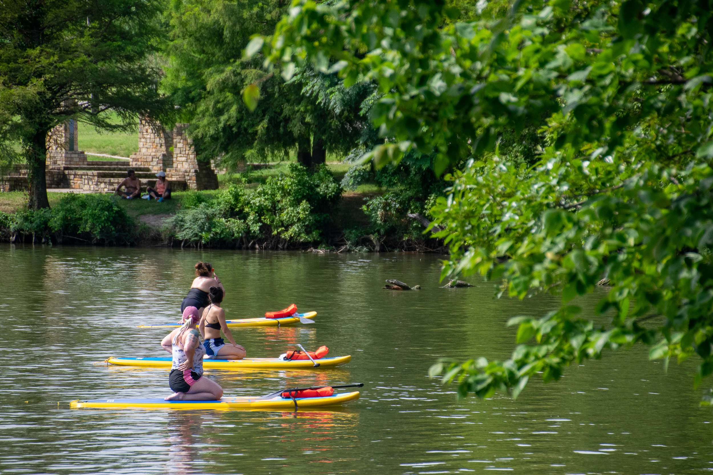 Three yogis await instruction while resting on their paddle boards.