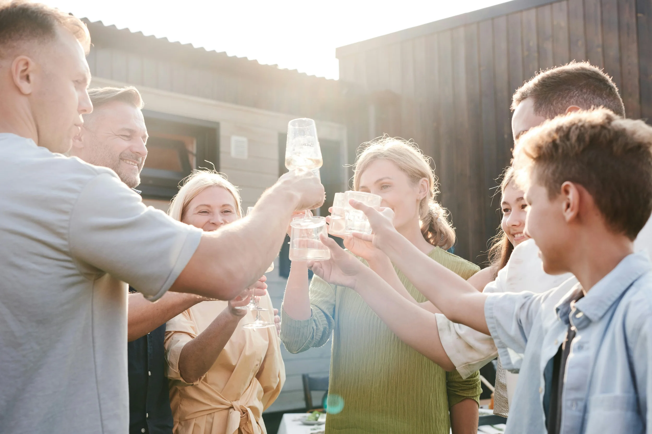 Group of people raising glasses in a toast outdoors during the daytime
