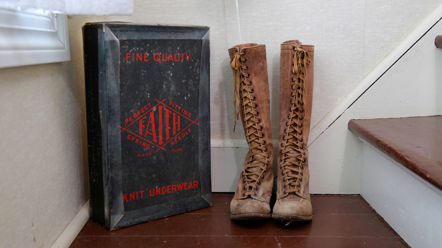 A pioneer's lace-up boots sit next to an antique  long underwear box.