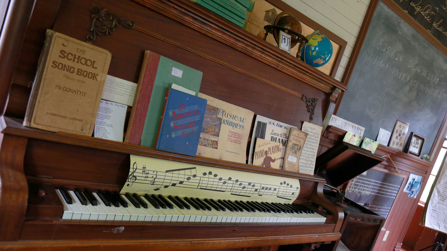 An old upright piano with school song books. 