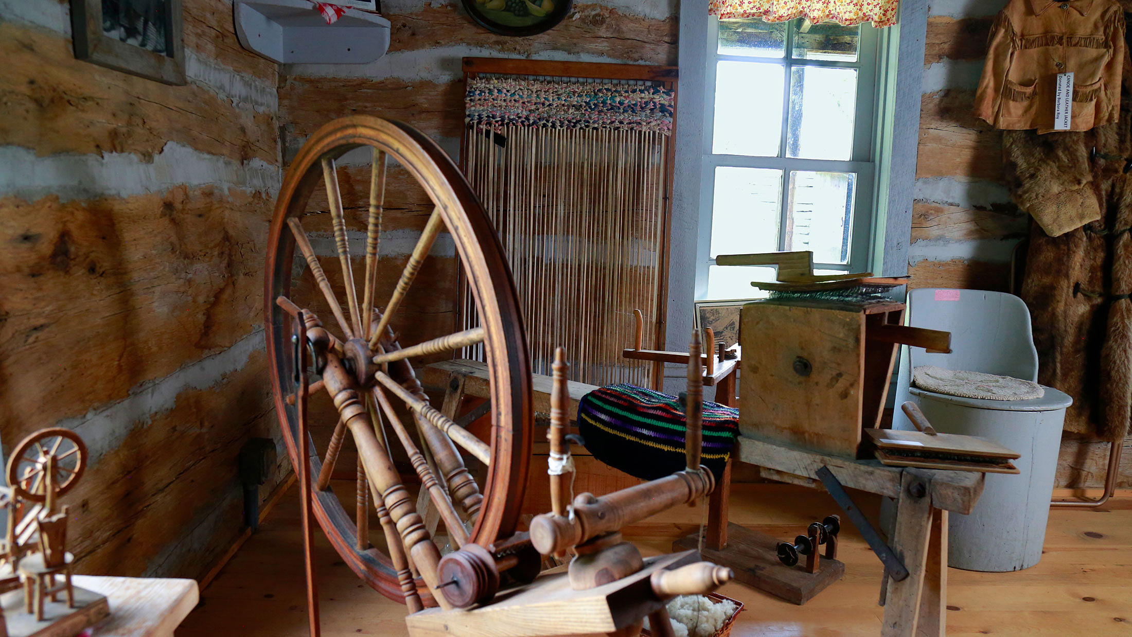 Interior view of a log cabin with spinning wheel
