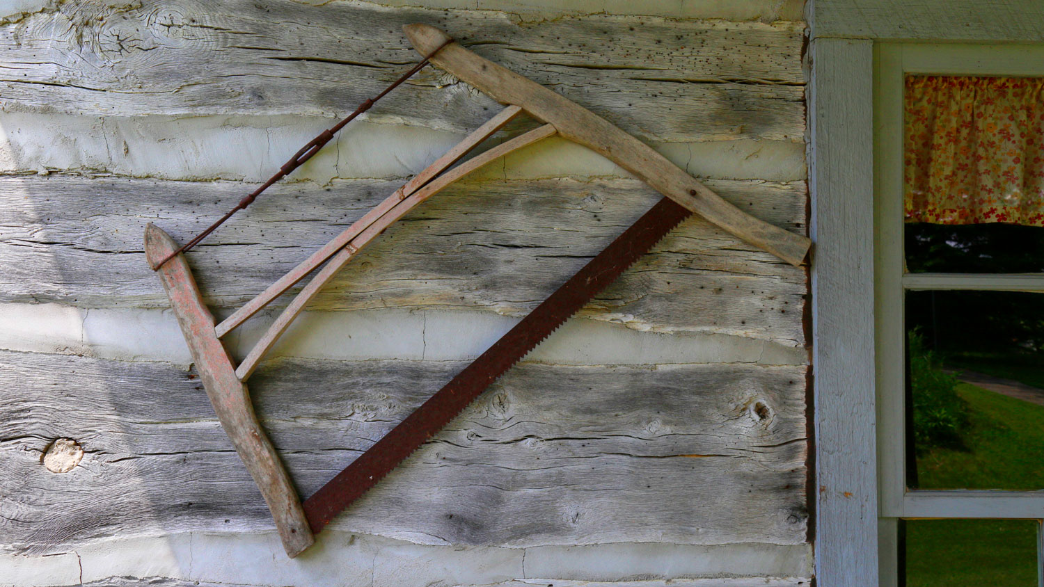 an old saw hangs outside the log cabin