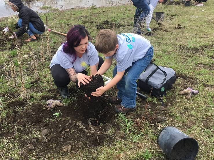 Caitlin Perry plants a tree with her son on Earth Day.jpg